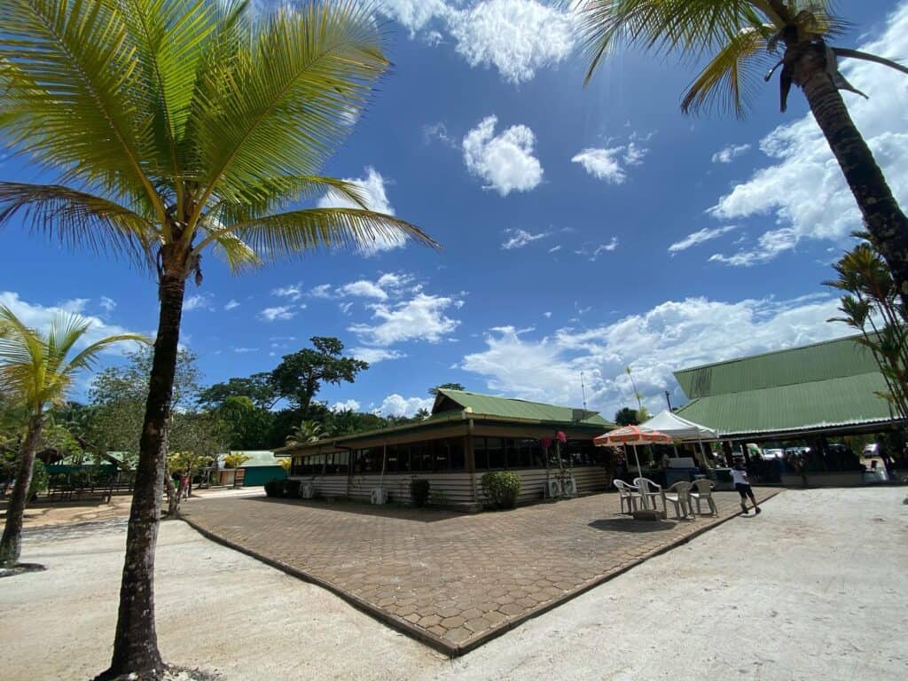 Restaurantgebouw met terras tussen hoge palmbomen op het resortterrein
