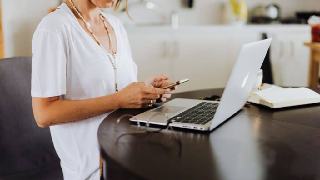 Backoffice medewerker werkt op afstand vanuit huis aan een laptop met notitieblok en telefoon