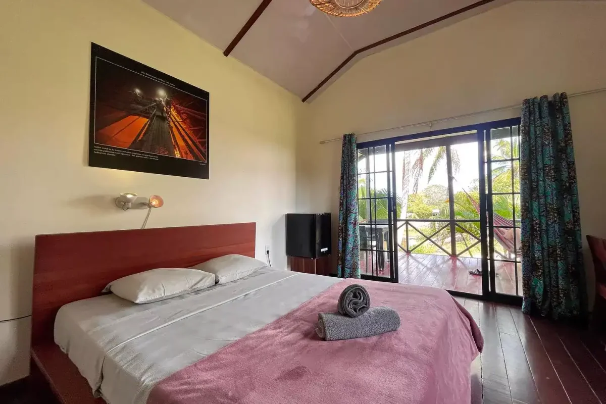 Slaapkamer in een cabana met tweepersoonsbed en openslaande deuren naar de veranda
