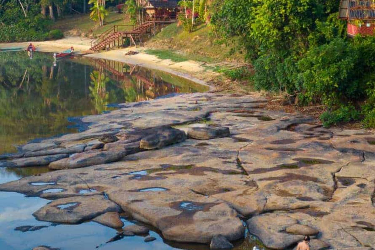 Rotsplaten en zandstrand bij Danpaati River Lodge aan de Boven-Suriname in de ochtend