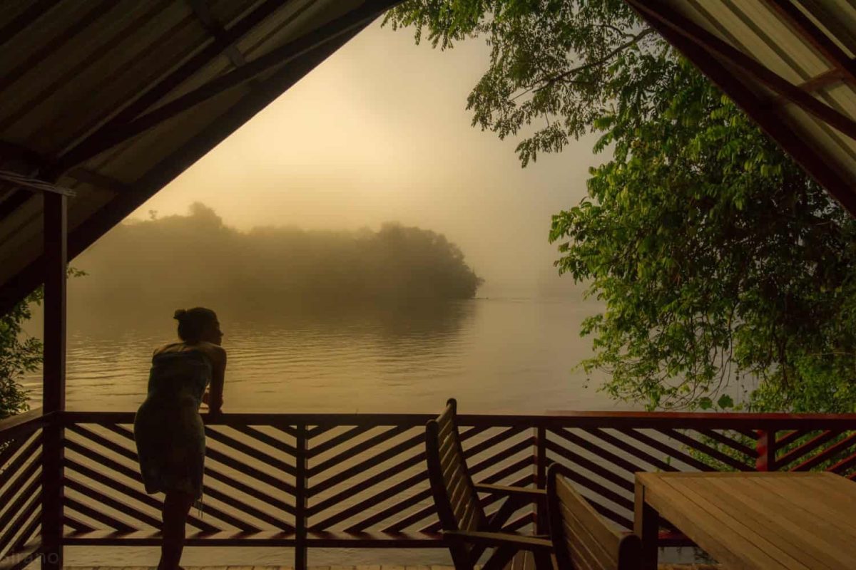 Uitzicht vanaf een veranda over de mistige Boven-Surinamerivier bij zonsopgang